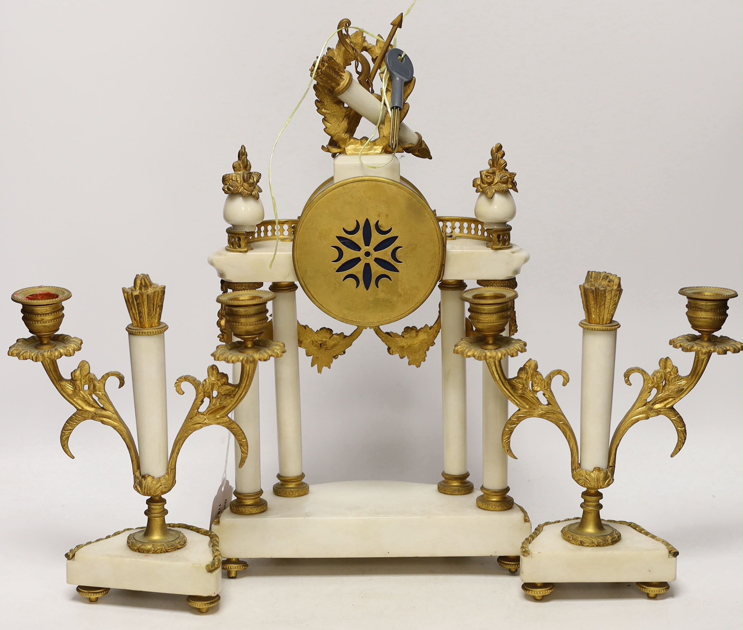 A 19th century French ormolu and white marble clock garniture striking on a gong, the dial decorated with swags, 40cm high